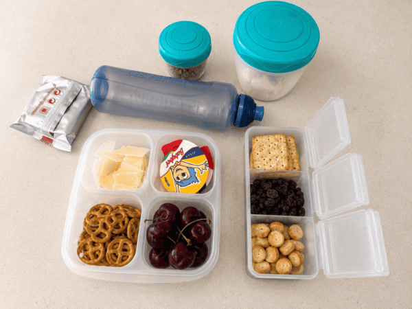 A mix of fruit, cheese, crackers and small treats packed into leak-proof containers. Familiar snacks can make a huge difference during delays, take-off and long waits at the gate.